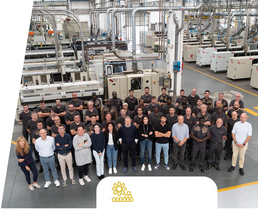 Gruppenfoto des Eredi Baitelli Teams in der Produktionshalle mit Fertigungslinien und Maschinen im Hintergrund.
