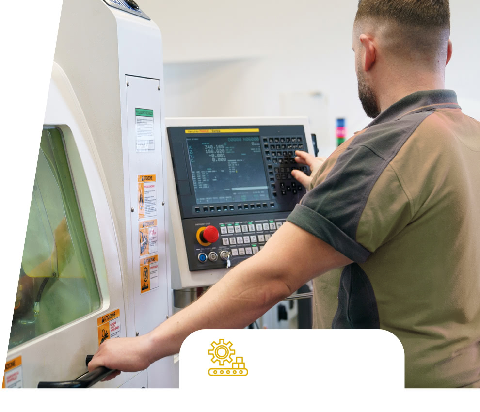 Eredi Baitelli Mitarbeiter am Bedienpult einer CNC-Maschine neben der Schutzverkleidung.